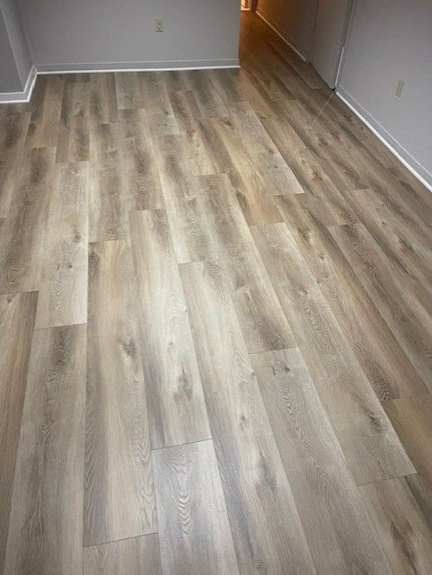 A room with a wooden floor and a gray wall.