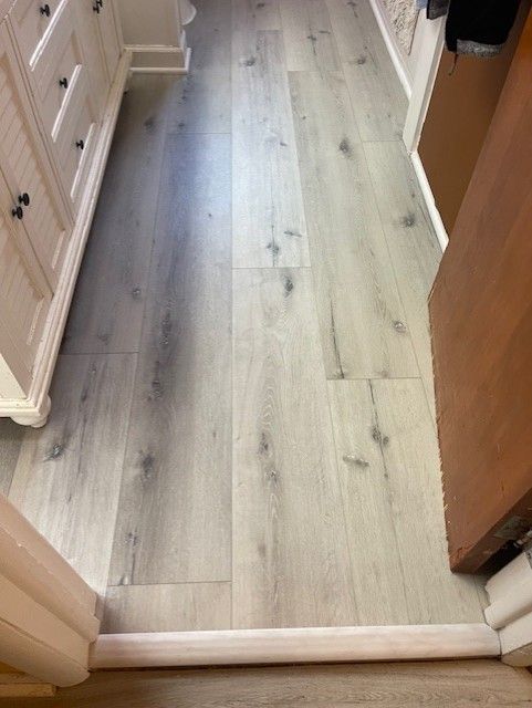 A bathroom with a hardwood floor and a door leading to it.