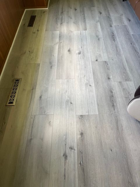 A person is standing on a white wooden floor in a room.