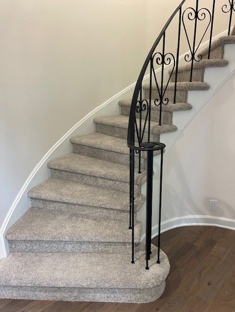 A curved staircase with a wrought iron railing