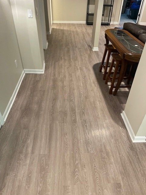 A hallway with a wooden floor and a table and chairs.