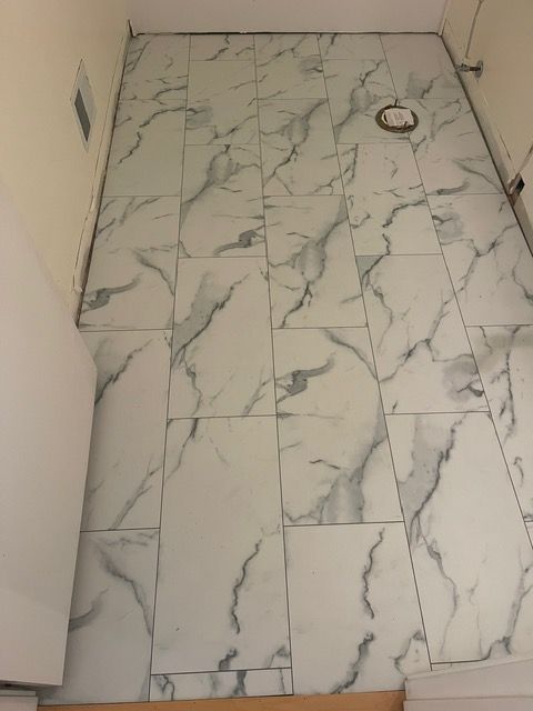 A bathroom floor with marble tiles and a toilet.