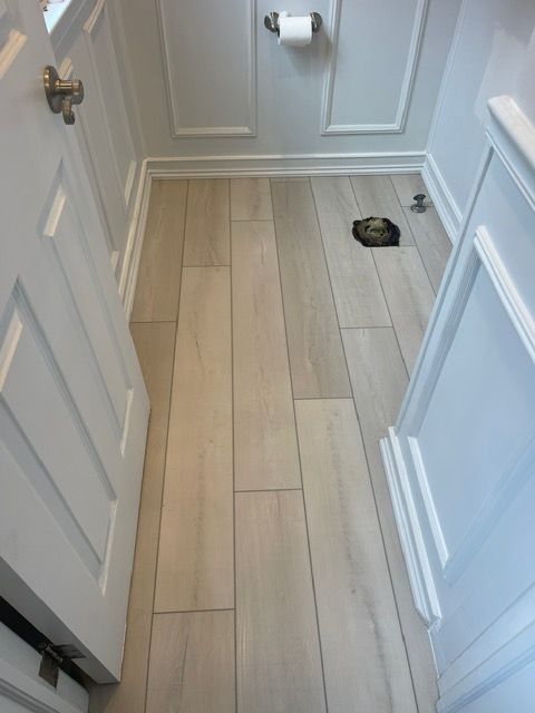 A bathroom with a wooden floor and white cabinets