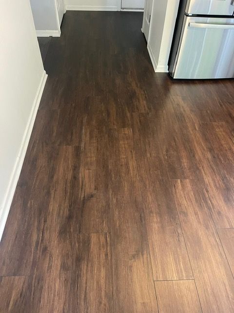 A kitchen with a wooden floor and a refrigerator.