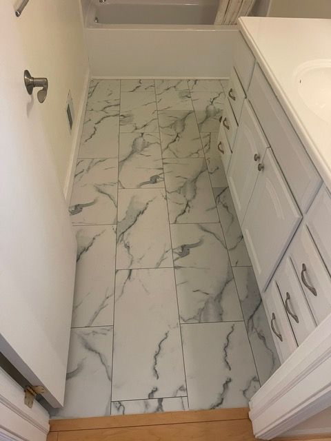A bathroom with marble tile floors and white cabinets