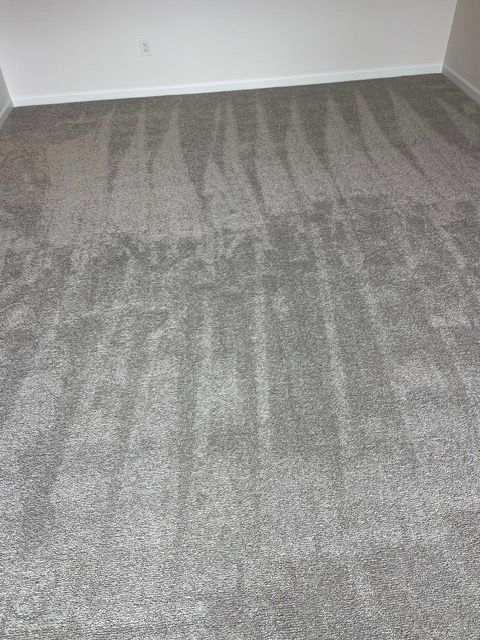 A room with a gray carpet and a white wall.