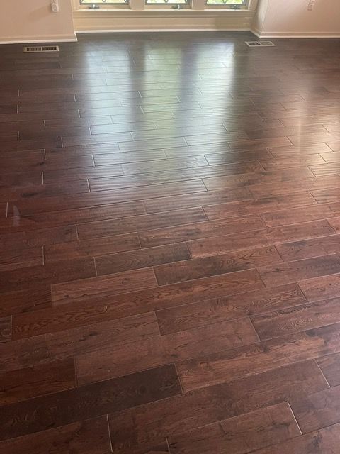 A living room with a wooden floor and two windows.