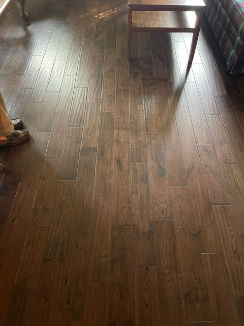 A person is standing on a wooden floor in a living room.