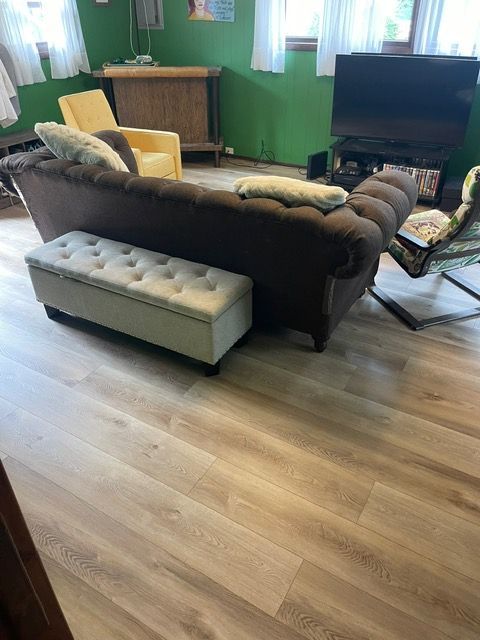 A living room with a couch , chairs , ottoman and television.