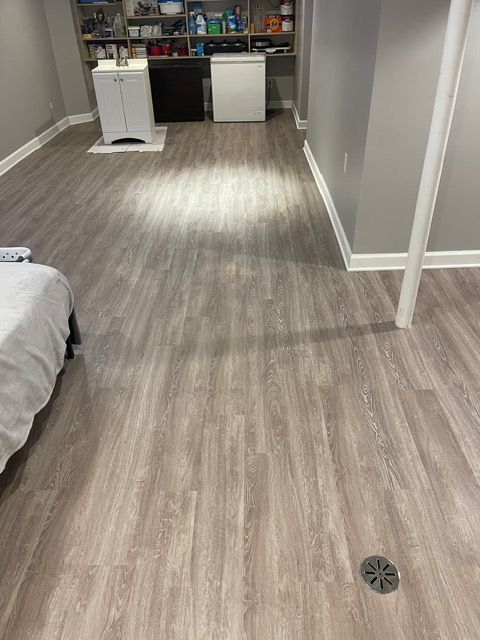 A bedroom with hardwood floors and a drain in the floor.