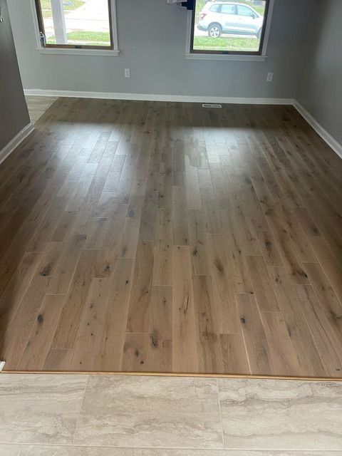 A living room with hardwood floors and a car parked in the background.