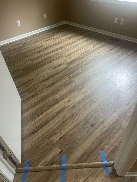 A room with a wooden floor and blue tape on the floor.