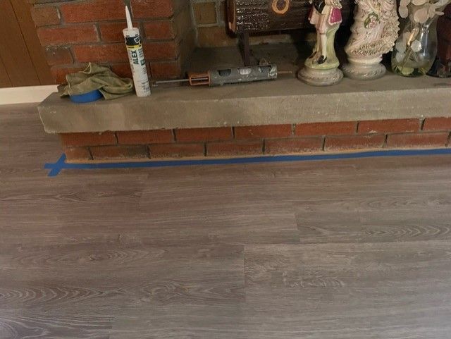 A brick fireplace with a wooden floor in front of it.