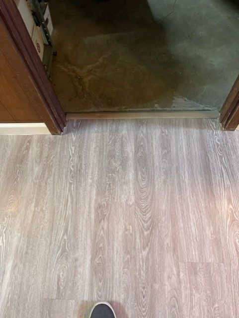 A person is standing on a wooden floor next to a door.