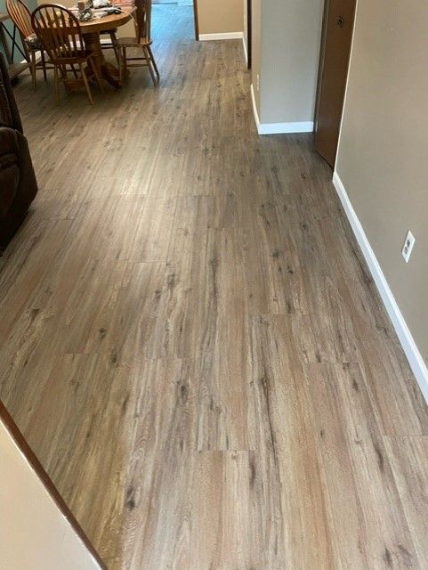 A hallway with a wooden floor and a dining room table and chairs.