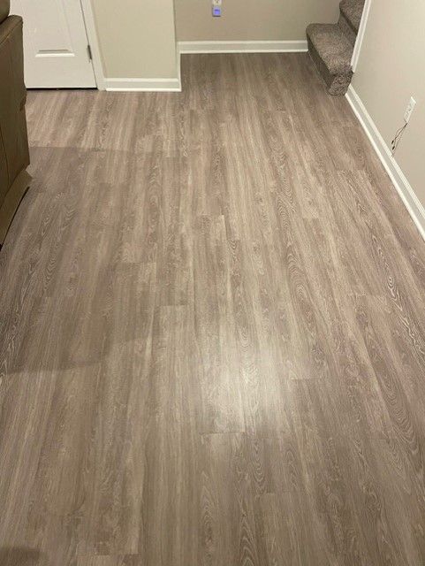 A living room with a wooden floor and stairs.