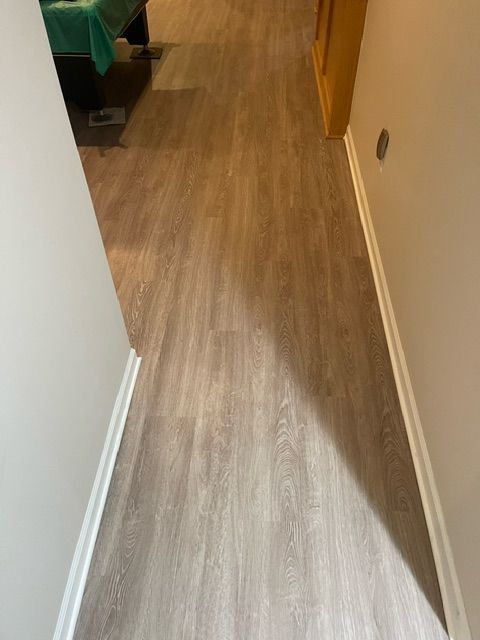 A hallway with a wooden floor and white trim.