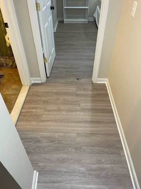 A hallway with a wooden floor and a door leading to a closet.
