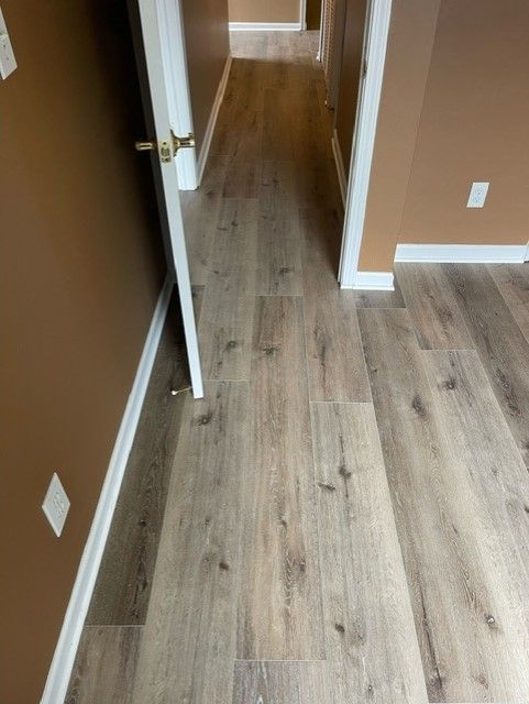 A hallway with hardwood floors and brown walls.