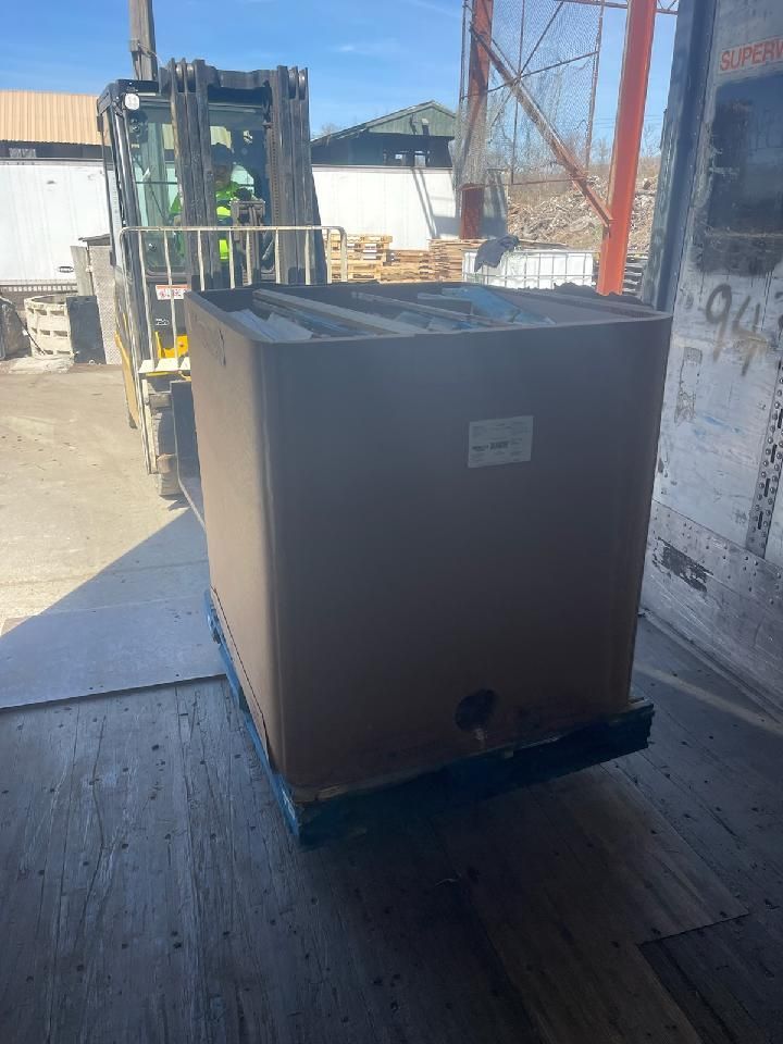 A forklift is loading a large cardboard box into a truck.