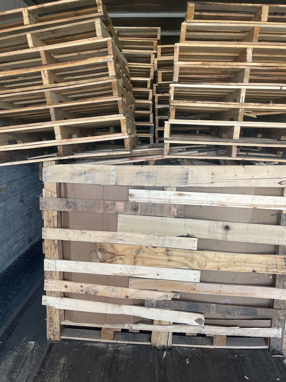 A pile of wooden pallets are stacked on top of each other.