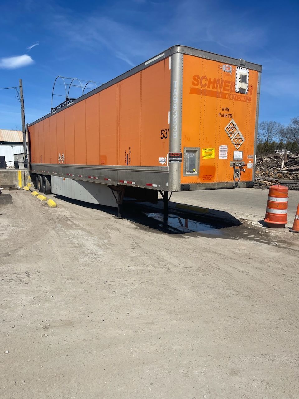An orange semi truck is parked on the side of the road.