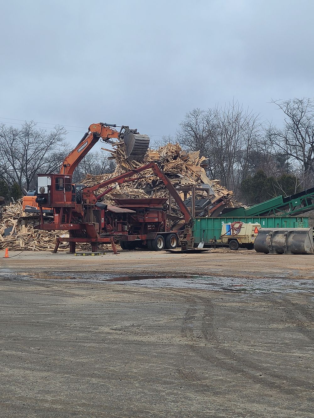 A large pile of wood is being loaded onto a truck.