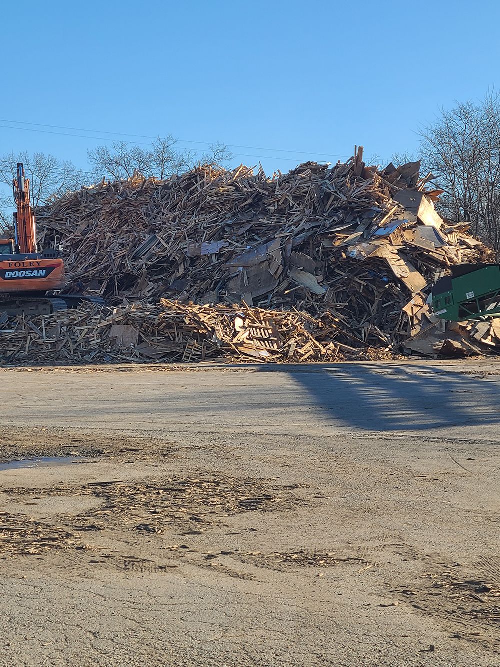 A large pile of wood is sitting in the middle of a dirt field.
