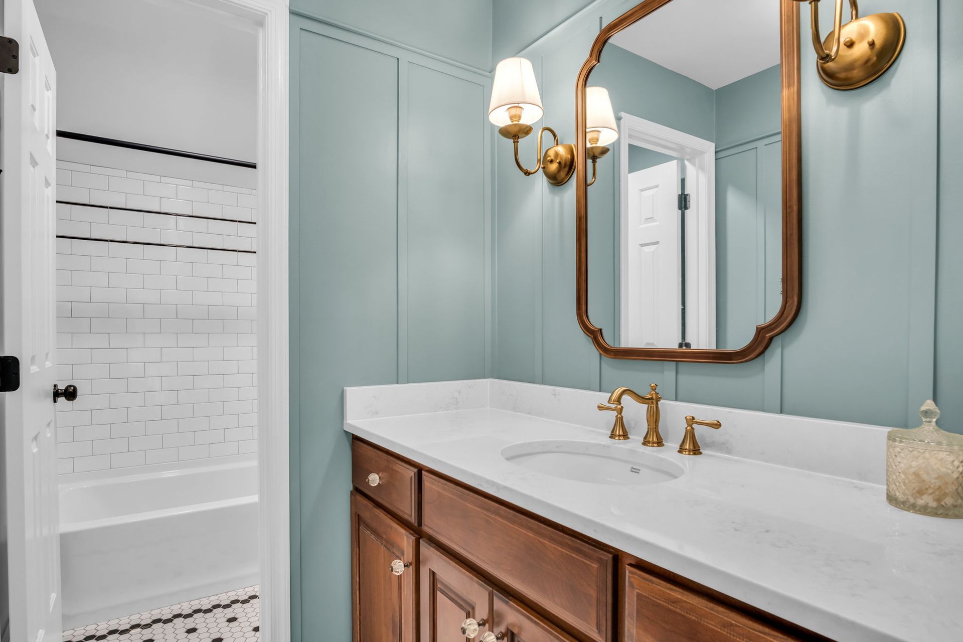 A bathroom with a sink , mirror and shower.