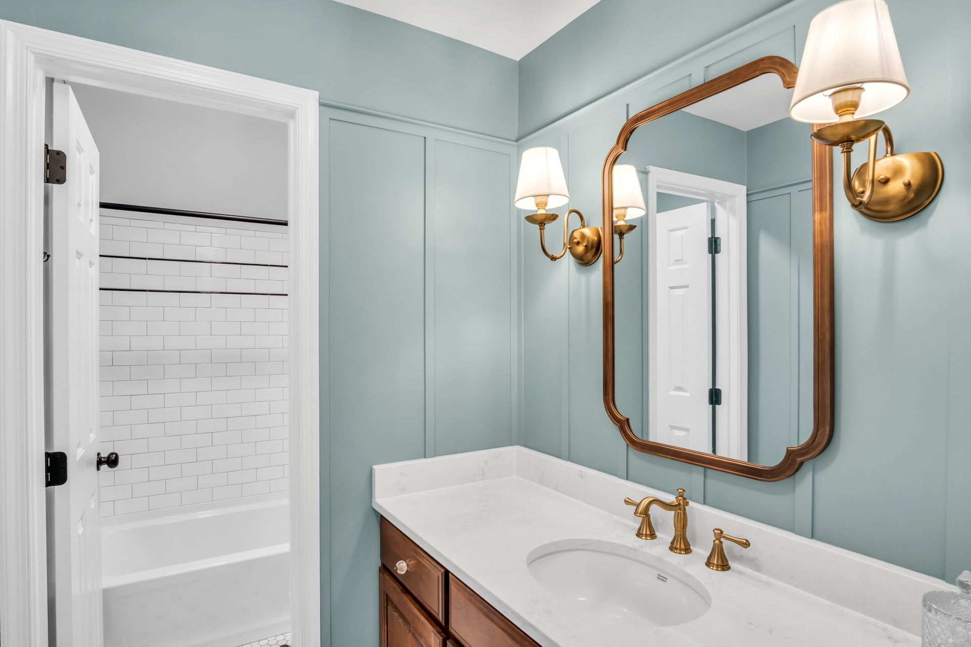 A bathroom with a sink , mirror , and light fixtures.
