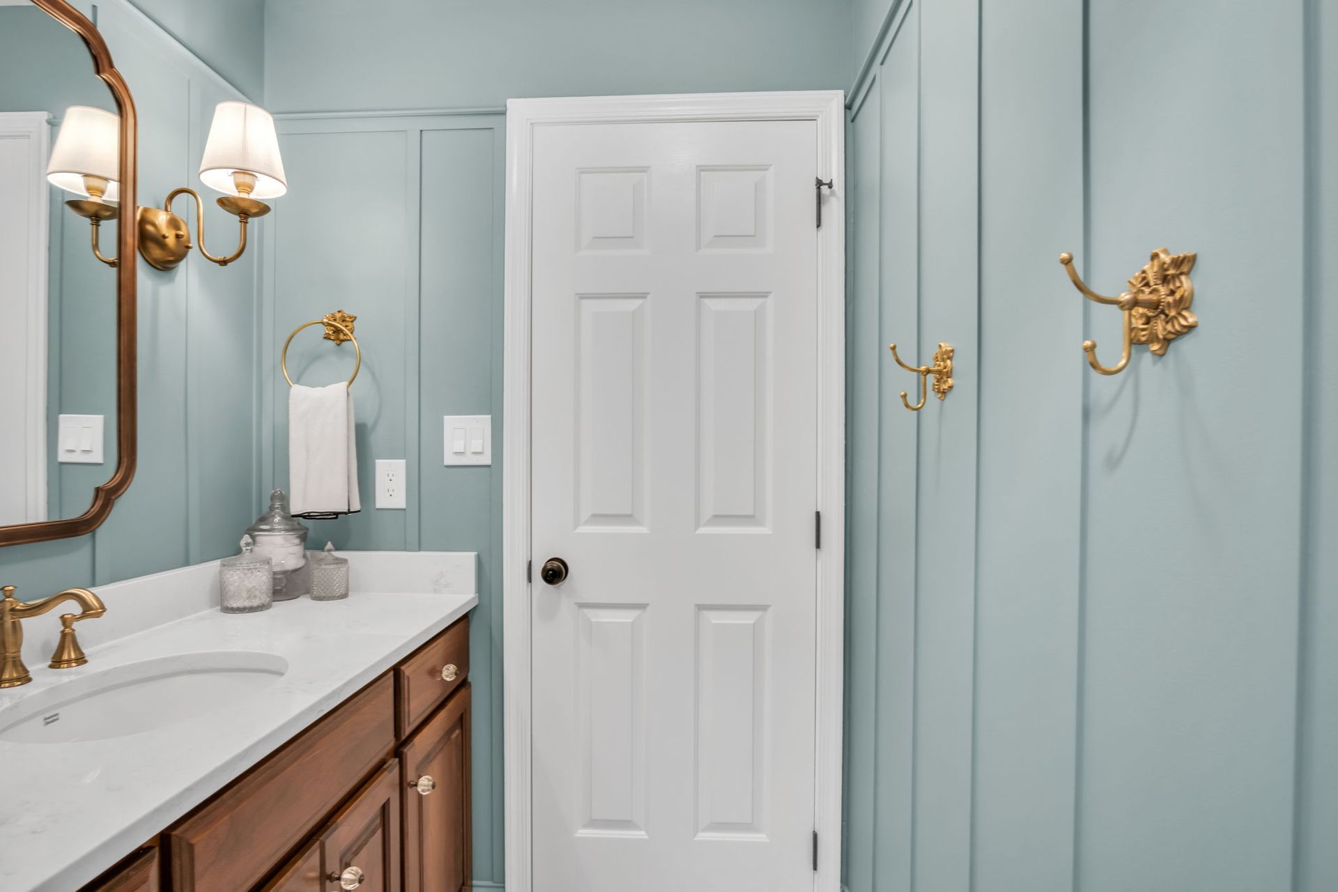A bathroom with blue walls , a sink , a mirror and a door.
