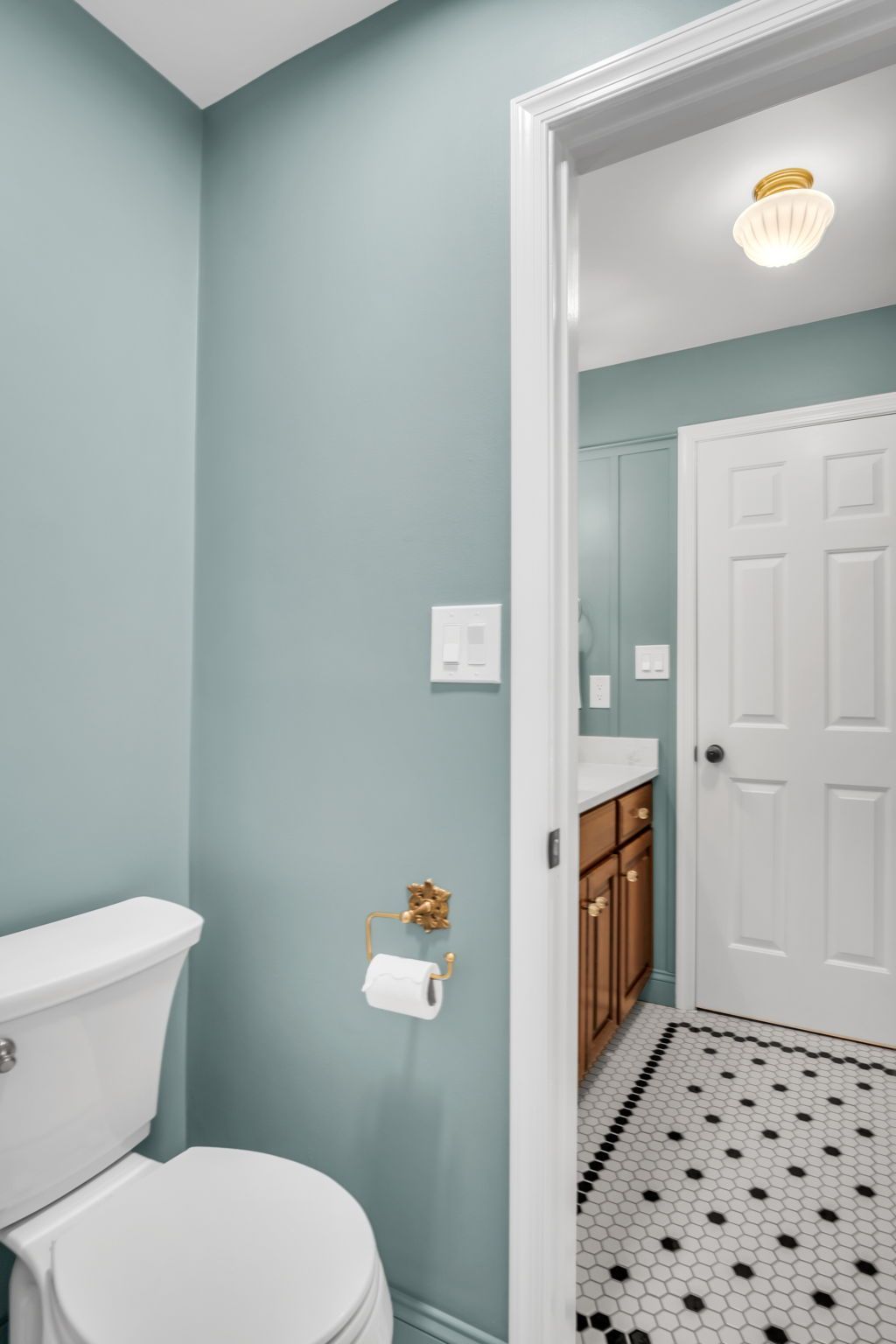 A bathroom with a toilet , sink and mirror.
