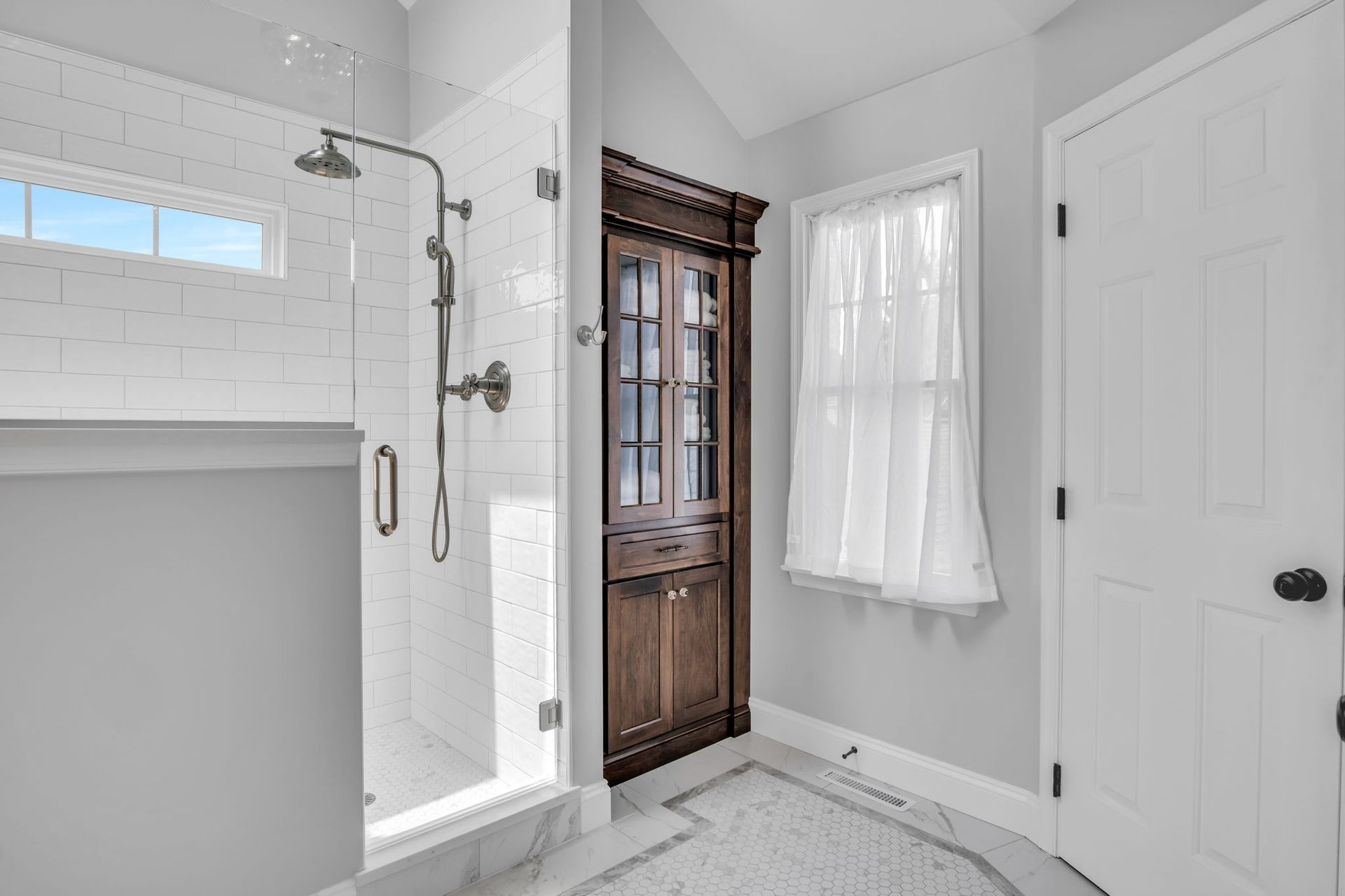 A bathroom with a walk in shower and a window.
