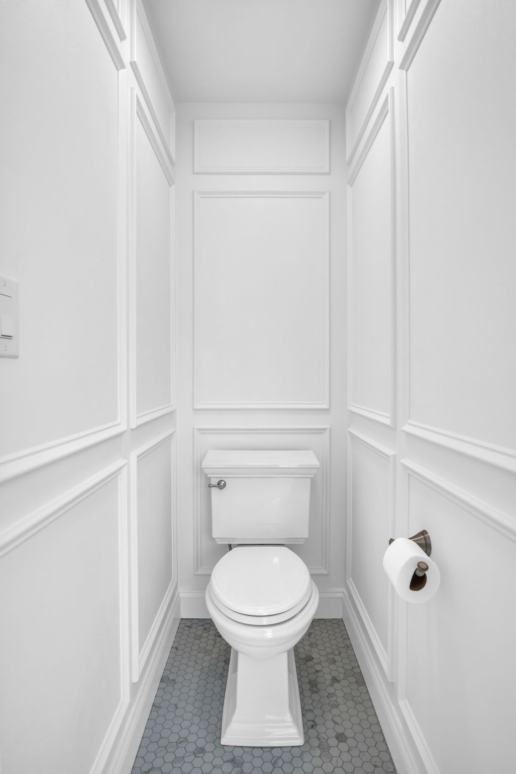 A small bathroom with a toilet and a paper towel holder.