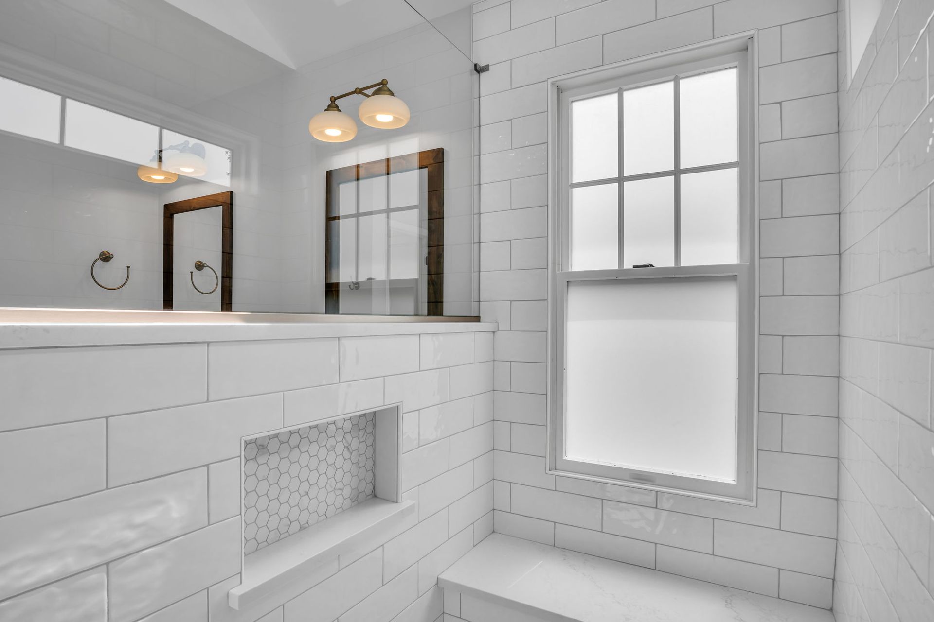 A bathroom with white tiles and a window.