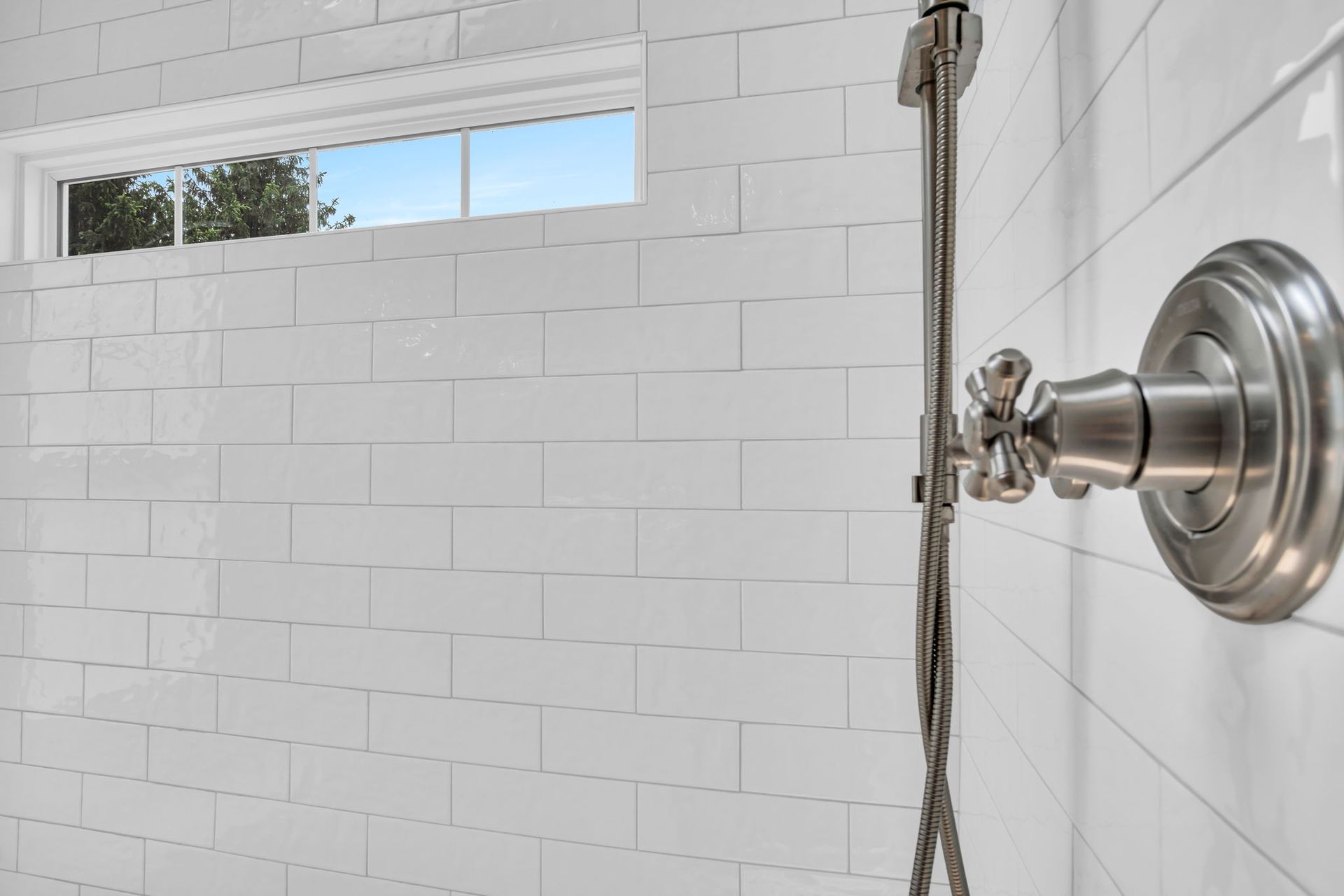 There is a window in the shower with a shower head.
