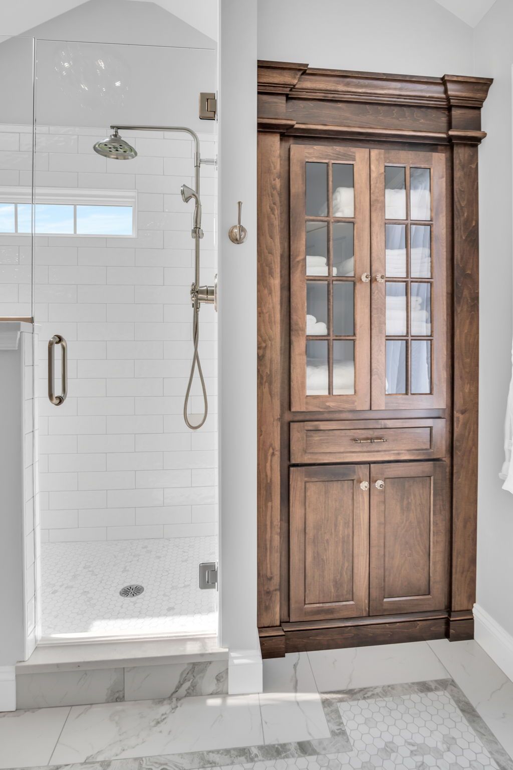 A bathroom with a walk in shower and a wooden cabinet