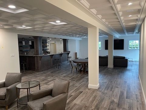A basement with a bar , tables , chairs , and a television.