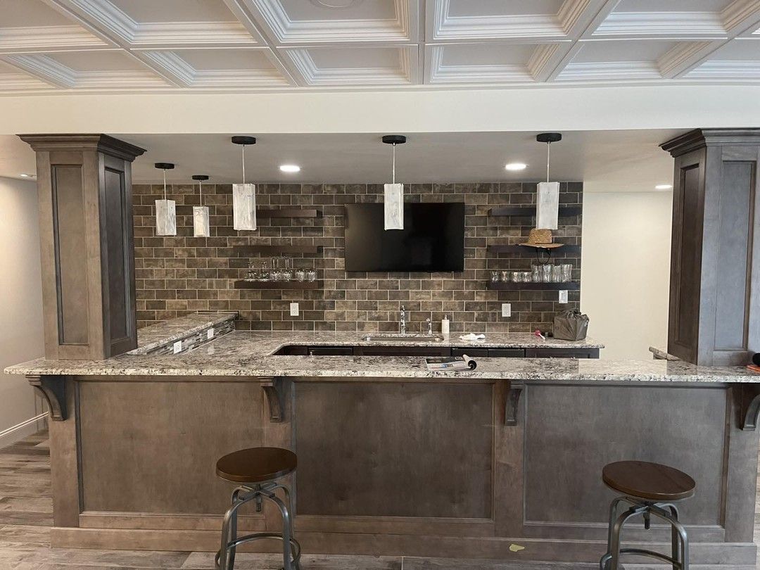 A kitchen with a bar and stools and a brick wall.