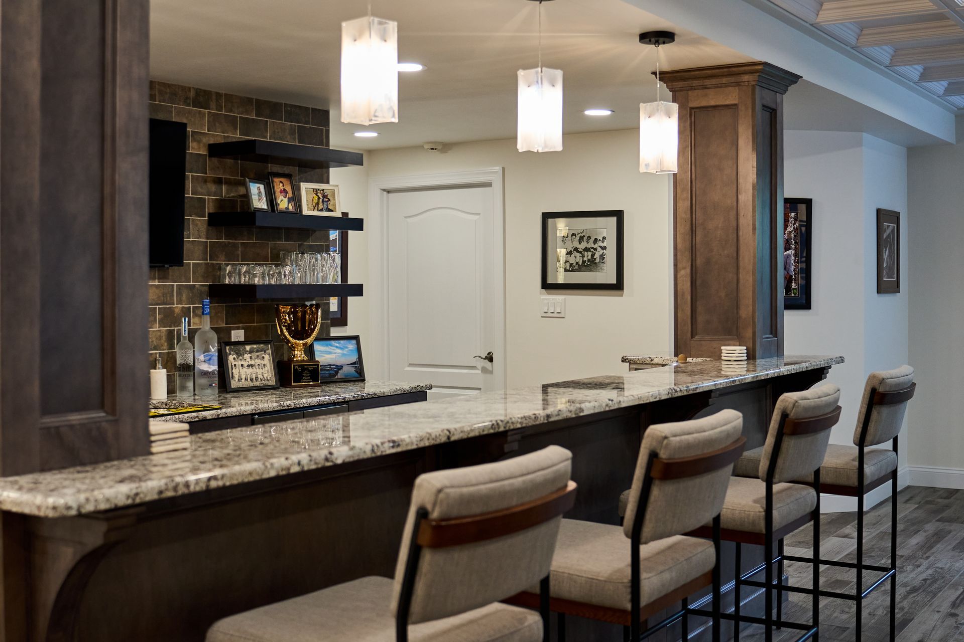 A bar in a basement with a long counter and chairs.