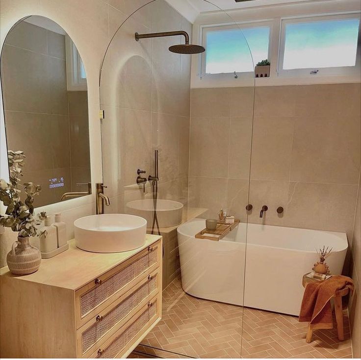 A bathroom with a tub , sink , mirror and shower.