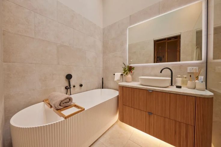 A bathroom with a bathtub , sink and mirror.