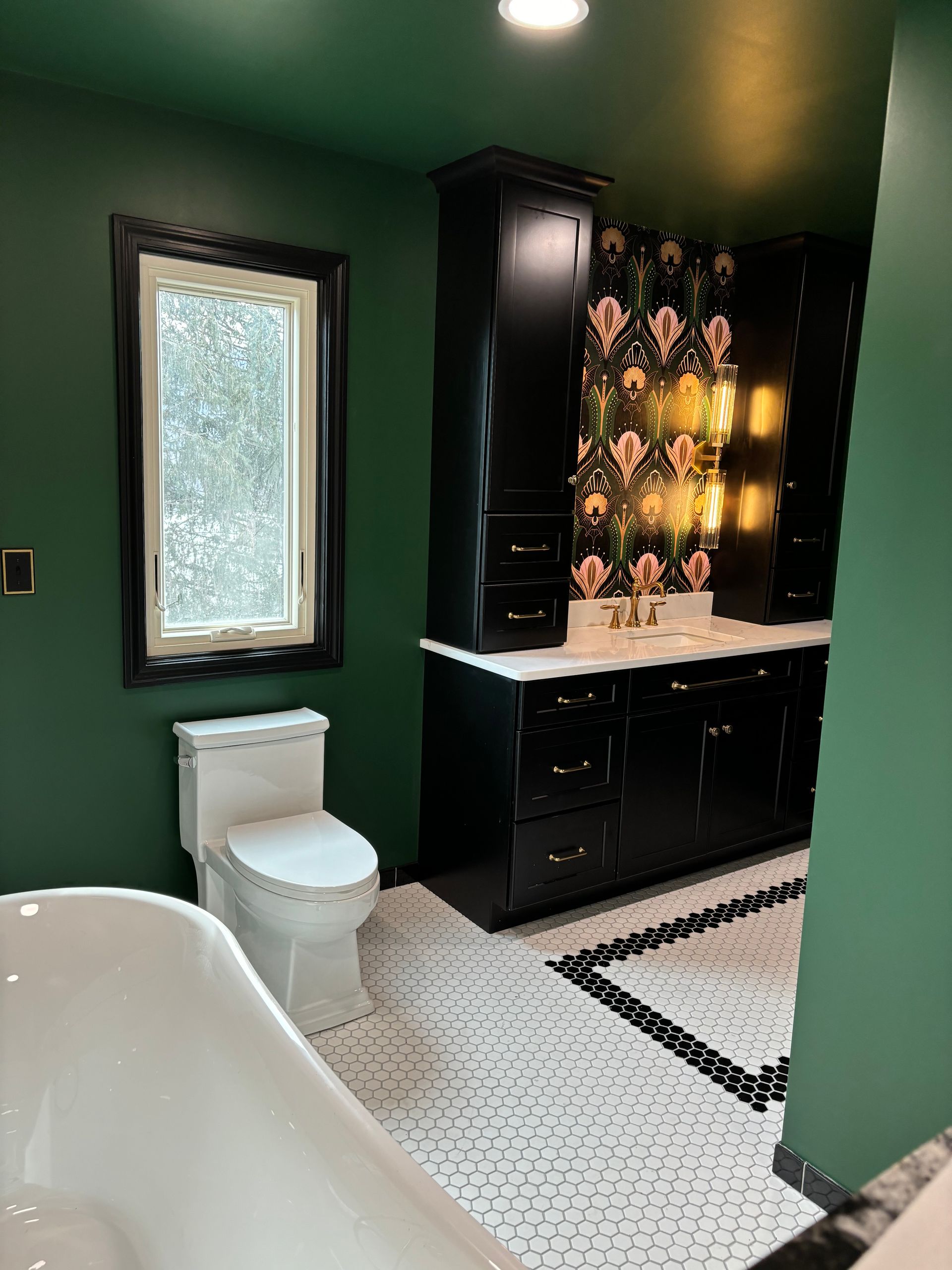 A bathroom with green walls , black cabinets , a toilet , and a bathtub.