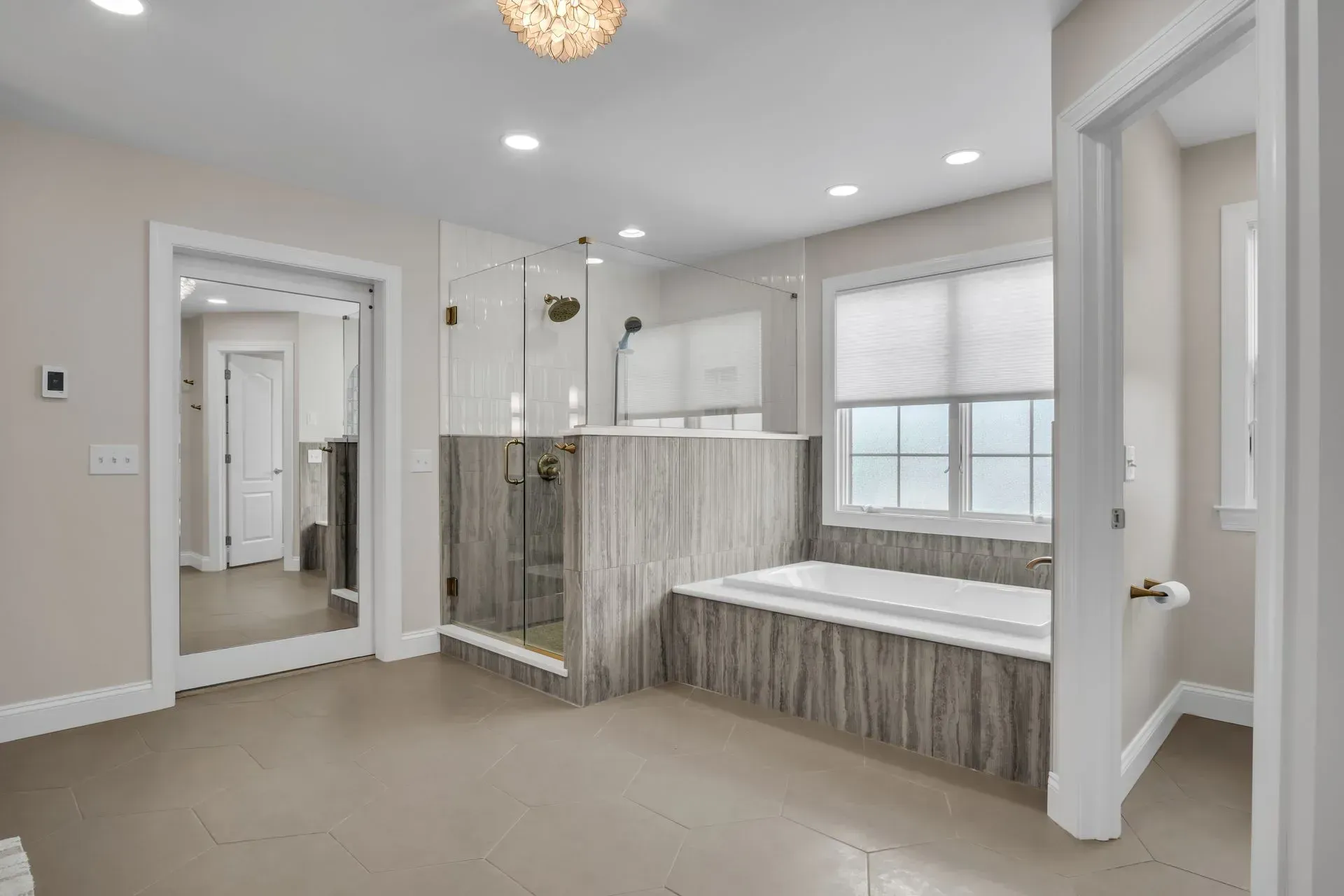 A large bathroom with a tub, a shower, and a mirror.