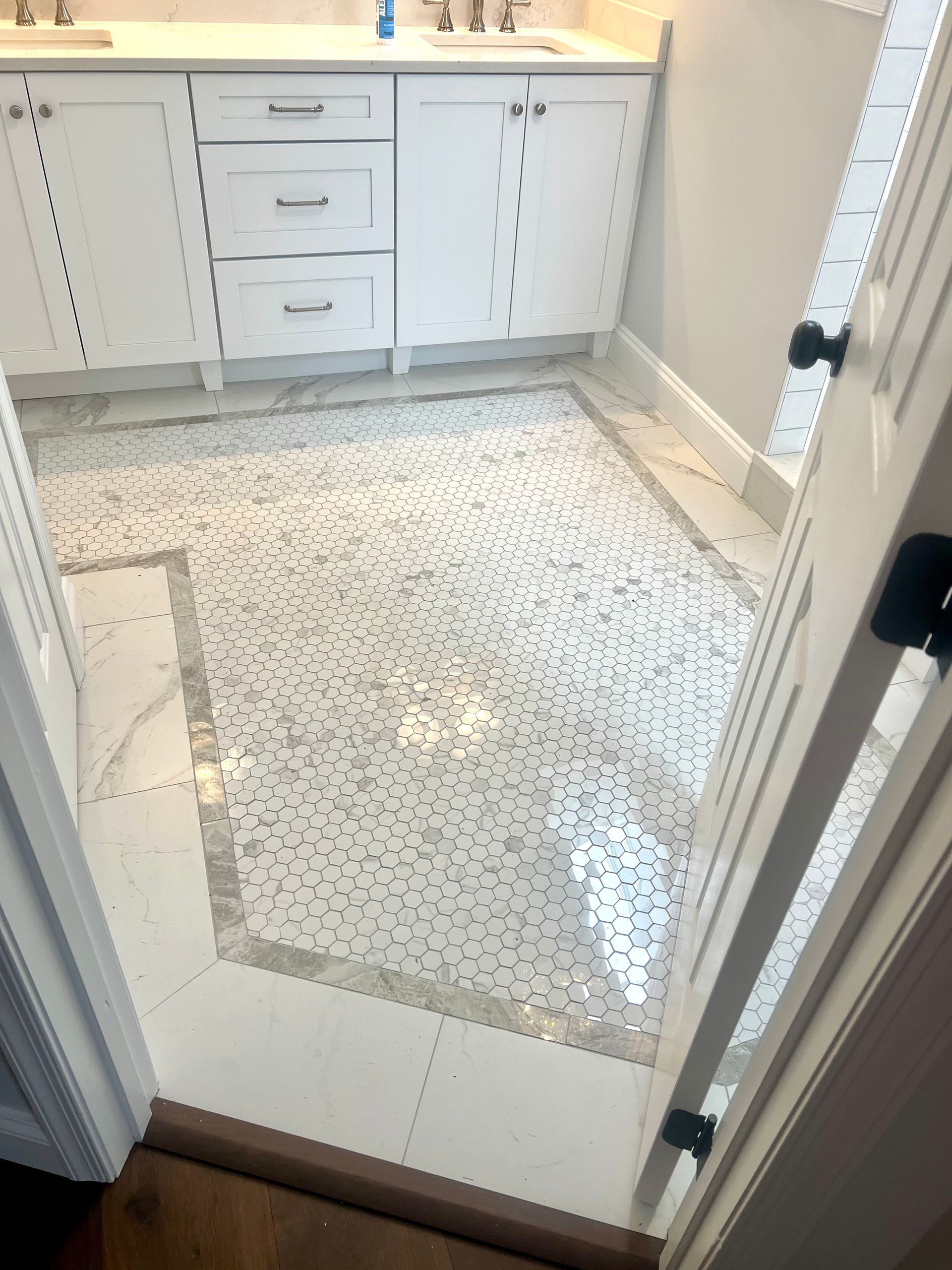 A bathroom with white cabinets and a tiled floor.