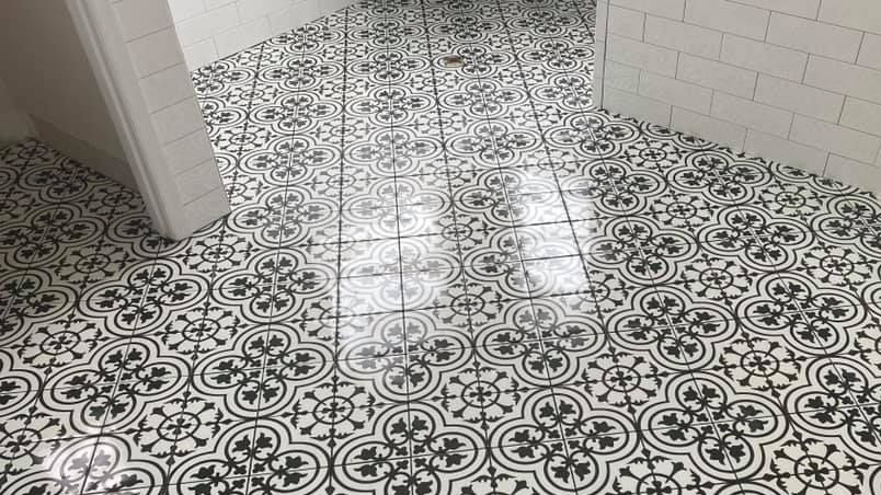 A black and white tile floor with a floral pattern in a bathroom.