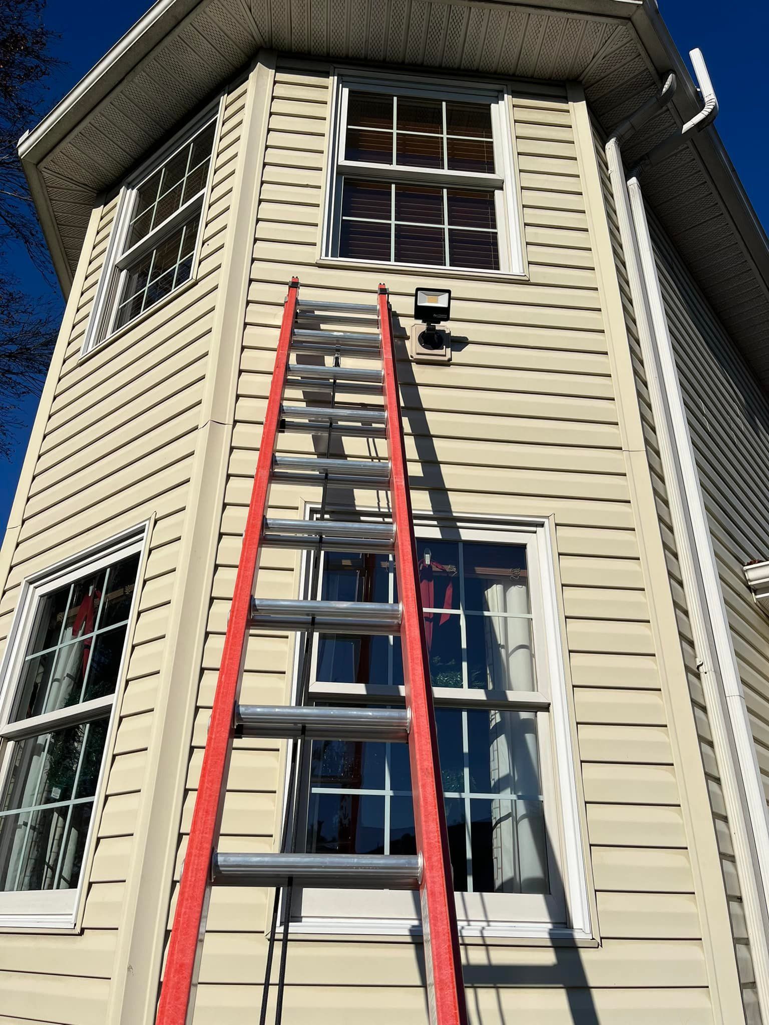 A red ladder is leaning against the side of a house.