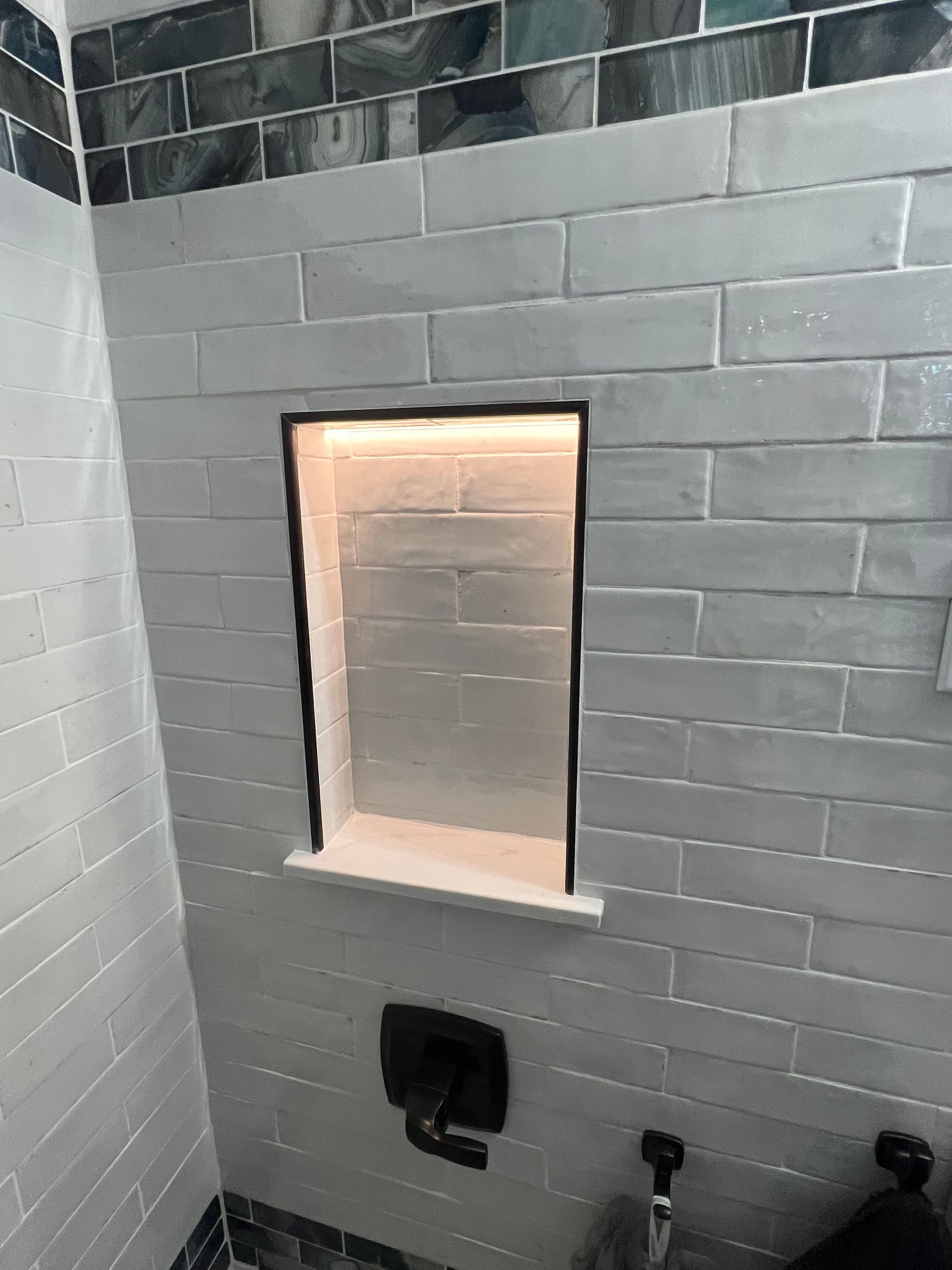 A bathroom with white tiles and a window in the wall.