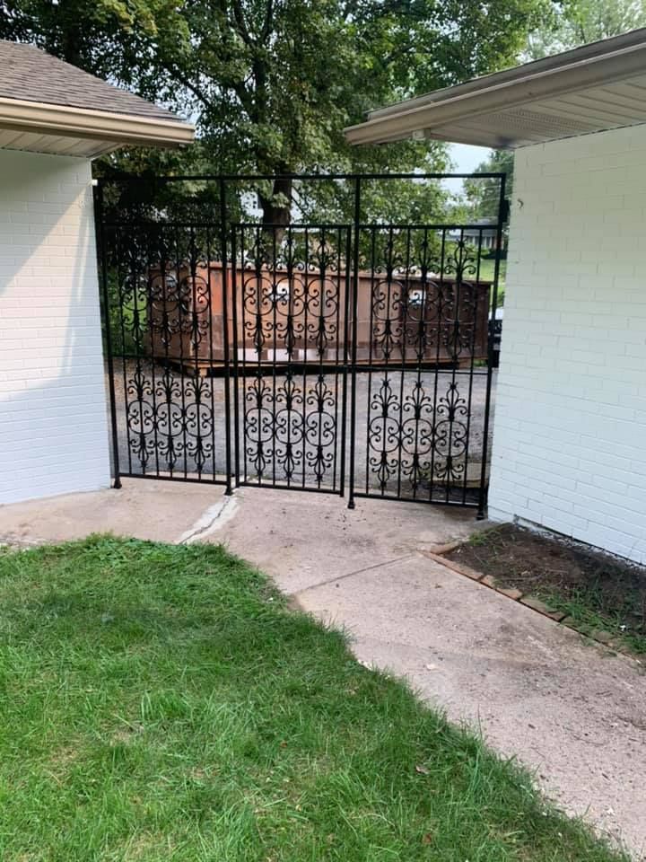 There is a wrought iron gate in the backyard of a house.