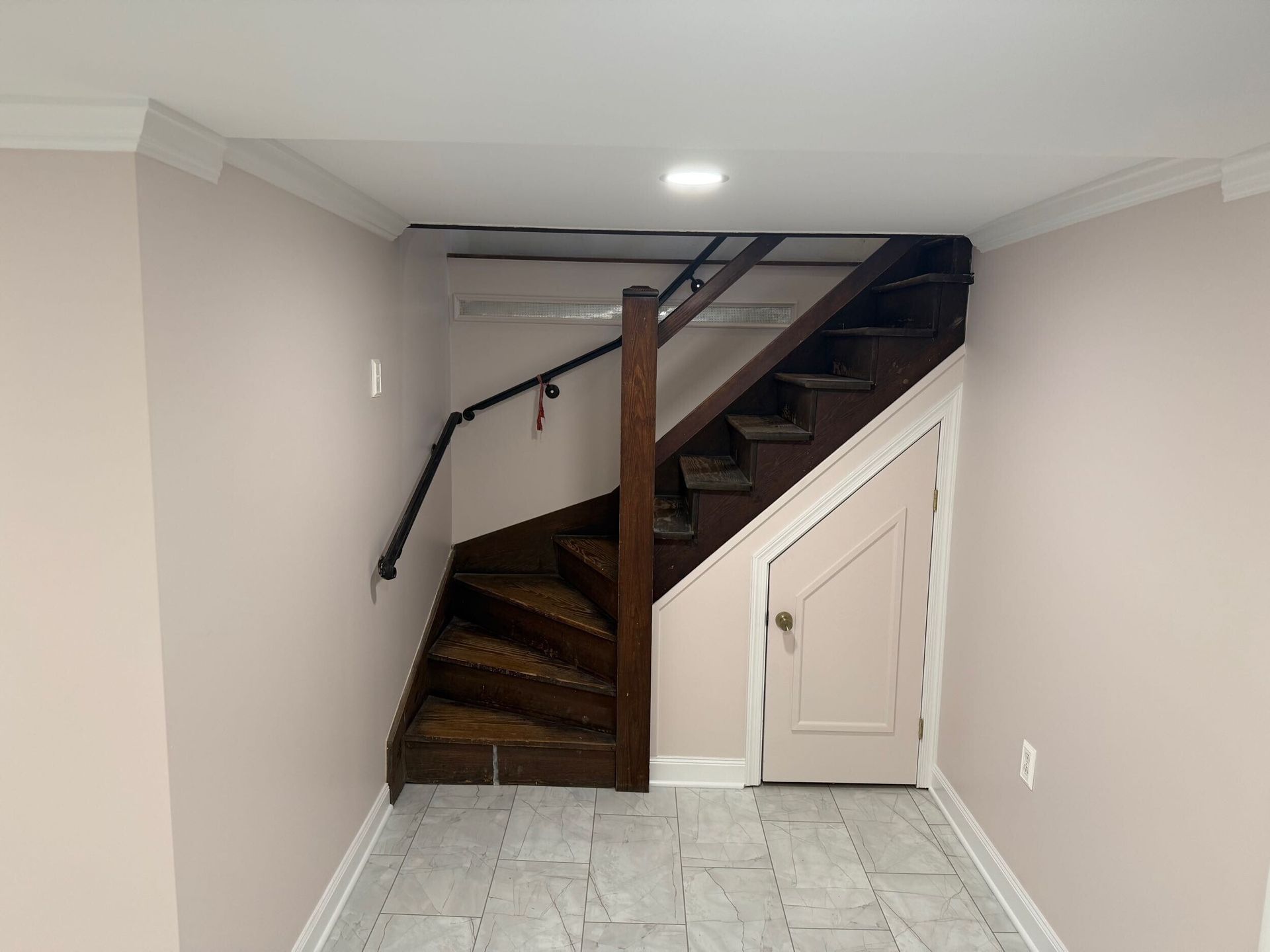 Basement with wooden stairs, handrails, a closed door.